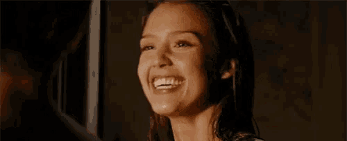 a woman is smiling and looking at a man in the mirror .