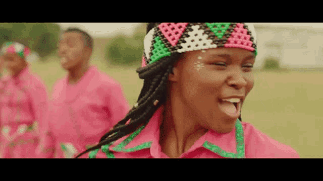 a woman wearing a pink shirt and a headband is standing in a field with other people .