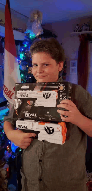 a boy holding two rival guns in front of a flag