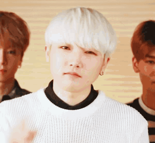 a young man with white hair is standing in front of two other men