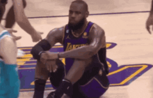 a basketball player is kneeling down on the court during a game .