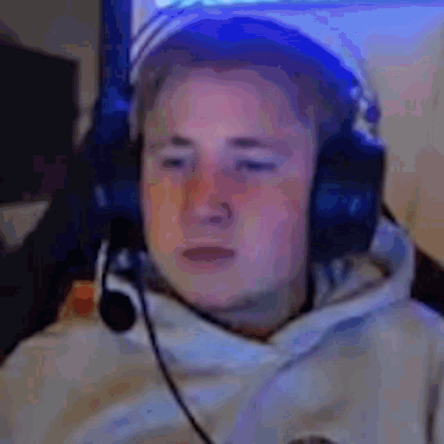 a man wearing headphones and a hat is sitting in front of a computer screen .