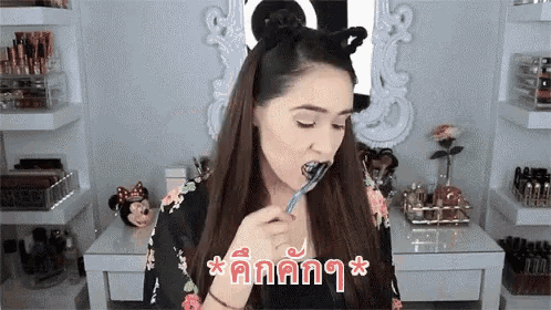 a woman is brushing her teeth with a toothbrush while wearing a headband with ears on it .