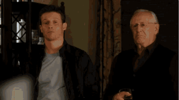 a man in a black jacket stands next to an older man
