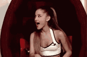 ariana grande is sitting in a chair with her mouth open and her eyes closed .