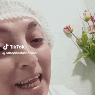 a woman wearing a shower cap is smiling in front of flowers