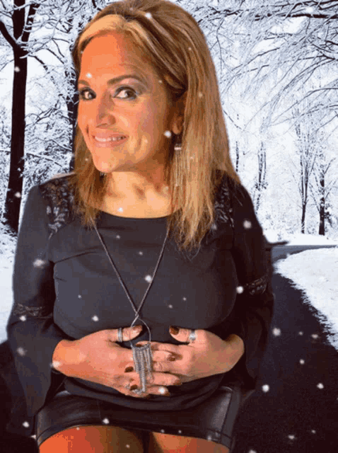 a woman in a black dress is smiling in front of snowy trees