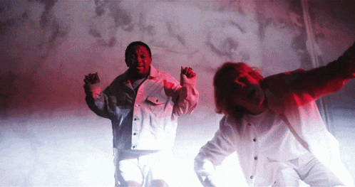 a man in a white jacket stands next to another man in a white shirt
