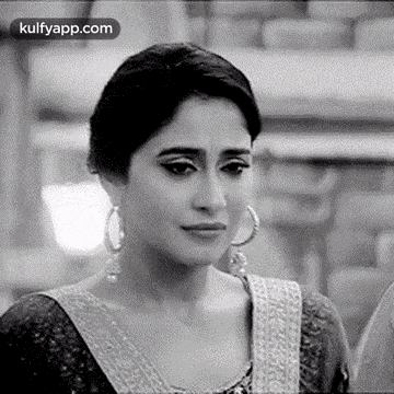 a black and white photo of a woman wearing earrings and a saree .