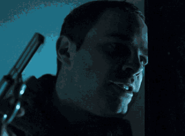 a man in a dark room holds a gun in his hand