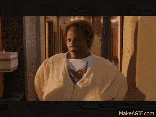 a woman in a yellow sweater is standing in a hallway looking at the camera .