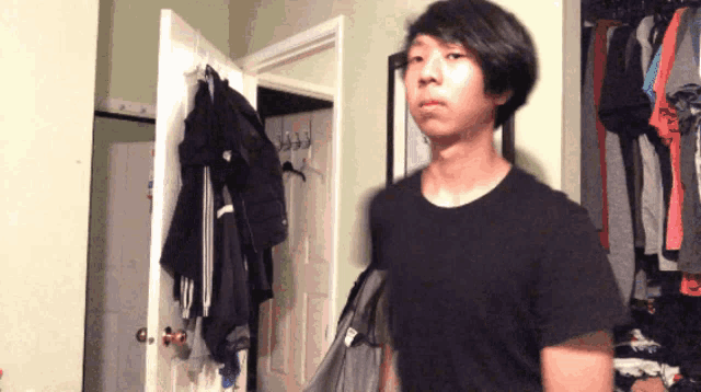 a man in a black shirt is standing in front of a closet