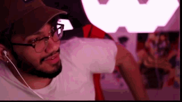 a man with a beard and glasses is wearing a hat and ear buds .