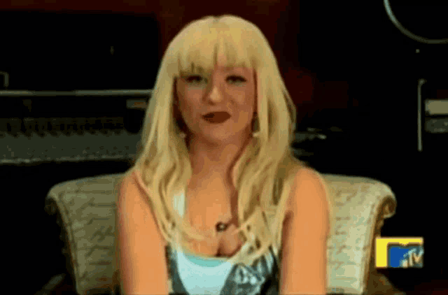 a blonde woman is sitting in a chair in front of a mtv sign