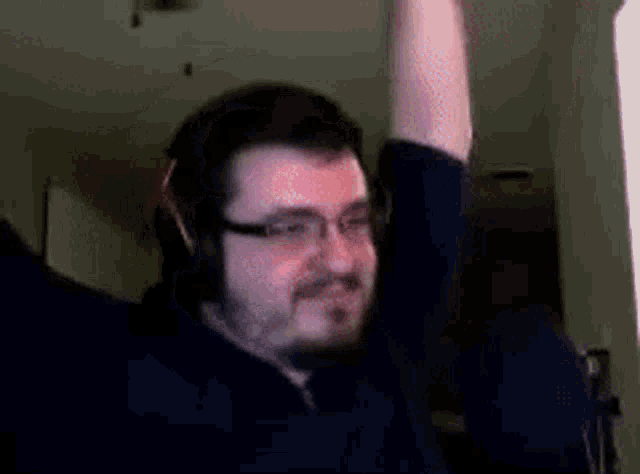 a man with glasses and headphones is raising his arm in the air