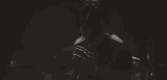 a black and white photo of a woman singing into a microphone on a stage .