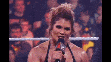 a woman is holding a microphone in front of a crowd .