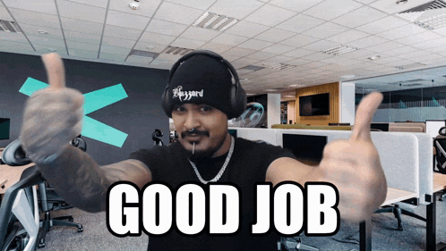 a man wearing headphones and a hat that says blizzard gives a thumbs up sign