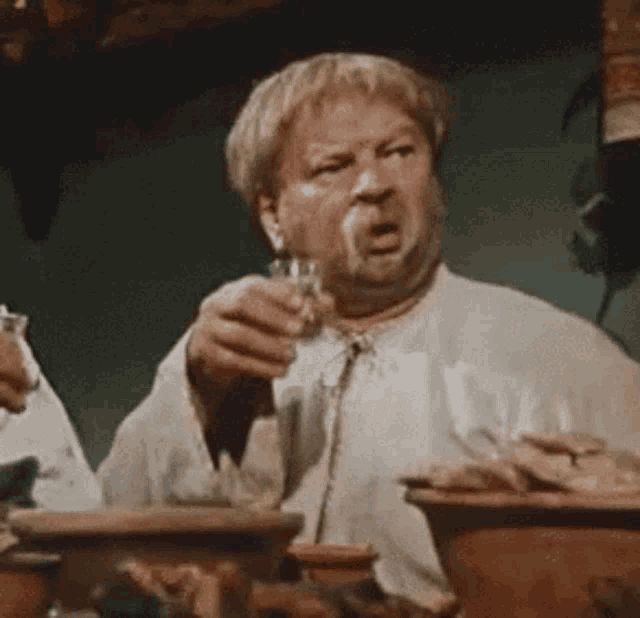 a man is sitting at a table drinking from a glass