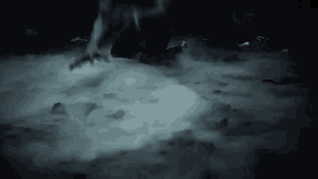 a person is standing in a dark room with smoke coming out of it .