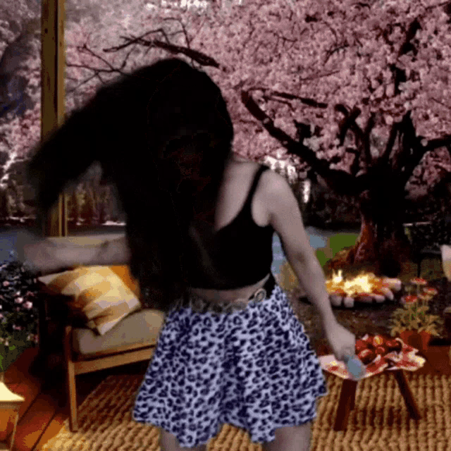 a woman wearing a leopard print skirt is dancing in front of a cherry blossom tree
