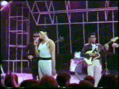 a group of men are standing on a stage playing instruments