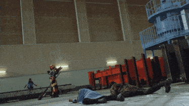 a man is laying on the floor in a room with a robot standing behind him