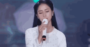 a woman is singing into a microphone on stage .