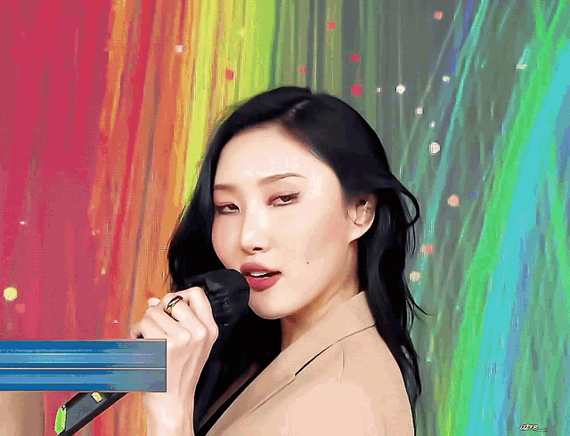 a woman singing into a microphone with a colorful background