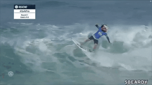 a person on a surfboard in the ocean with the word beardy in the corner