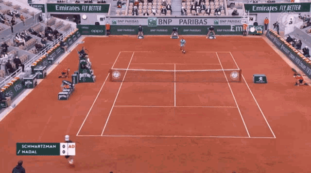 a tennis player stands on a court in front of an emirates advertisement