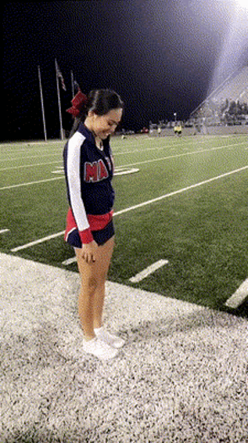 a cheerleader wearing a ma uniform stands on the sidelines