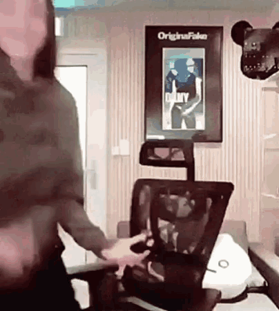 a woman is sitting in an office chair in front of a poster that says original fake on it