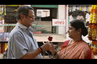 a man is giving a rose to a woman in front of a sign that says ' a '