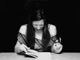 a woman is laughing while reading a book at a table