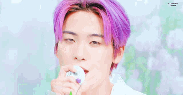 a close up of a person with purple hair holding a microphone