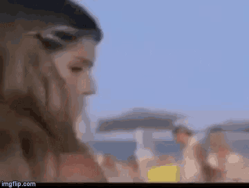 a blurry picture of a woman standing on a beach with umbrellas .