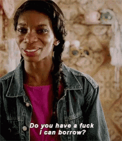 a woman in a pink shirt and denim jacket is smiling and asking do you have a fuck i can borrow .