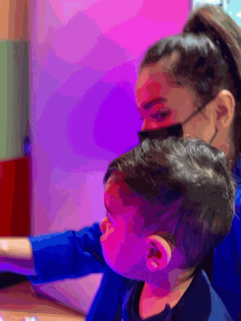 a woman wearing a mask sits next to a child
