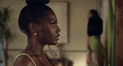 a woman with braids and hoop earrings looks to the side