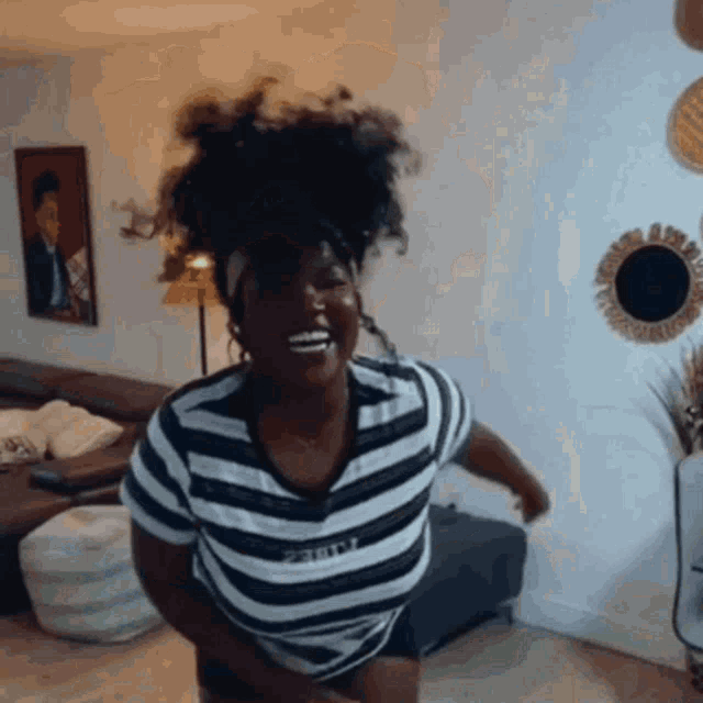 a woman wearing a black and white striped shirt is dancing in a living room .