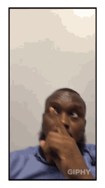 a gif of a man covering his mouth with his finger and the word giphy at the bottom