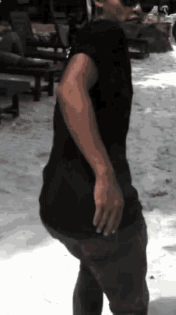 a man in a black shirt and grey pants is standing in the sand