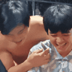 a shirtless man is playing with another shirtless man 's arm