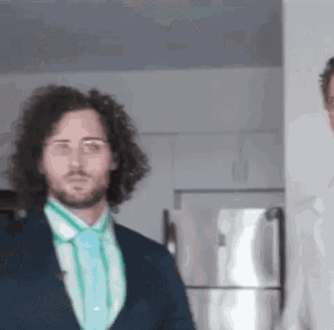 a man in a suit and tie is standing next to another man