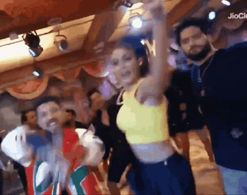 a group of people are dancing in a room with a woman in a yellow top .