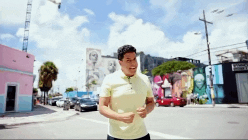 a man in a yellow shirt is running on a street