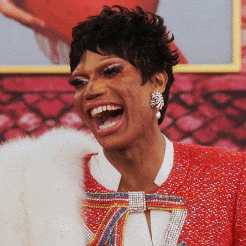 a woman wearing earrings and a red jacket is laughing with her mouth open