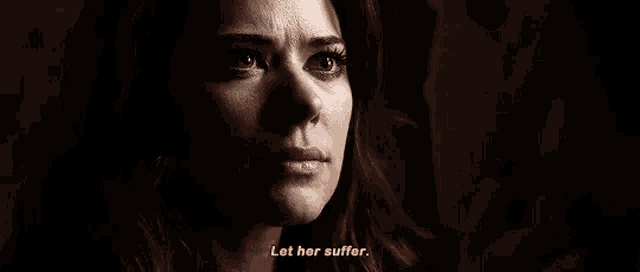 a close up of a woman 's face with the words `` let her suffer '' written on the bottom .