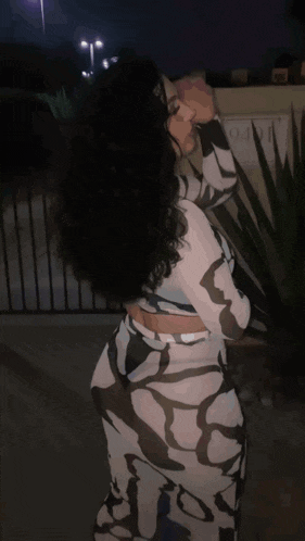 a woman in a zebra print dress stands in front of a fence and a sign that says ' motel ' on it